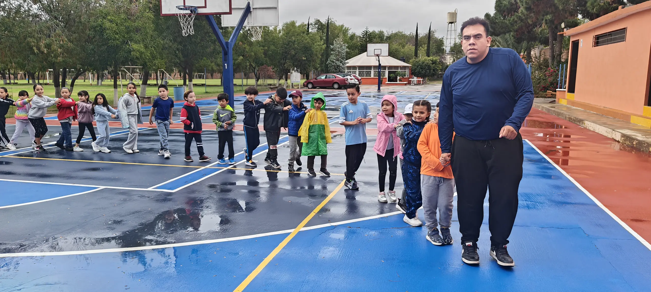 Fila de niños avanzando por la cancha detrás de su maestro